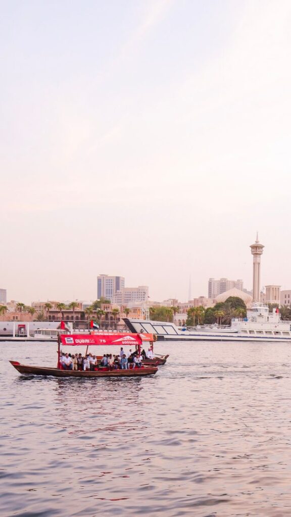 Mastering the First Impression: Your intriguing post title goes here Scenic view of a traditional boat on Dubai Creek with city skyline at sunset.