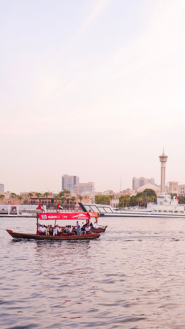 Mastering the First Impression: Your intriguing post title goes here Scenic view of a traditional boat on Dubai Creek with city skyline at sunset.